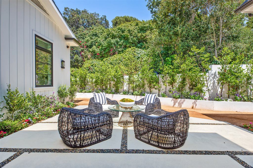 Backyard lounge patio with woven chairs against a garden wall, Bel-Air new construction