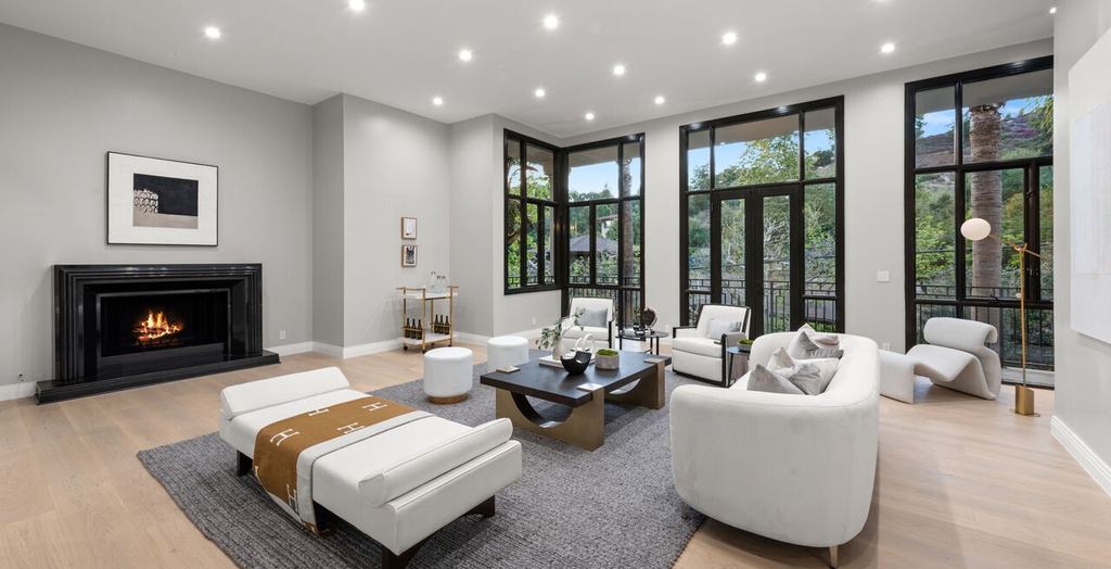 Living room with floor-to-ceiling black aluminum-clad divided-light windows and doors beside a black marble fireplace, Beverly Hills remodel