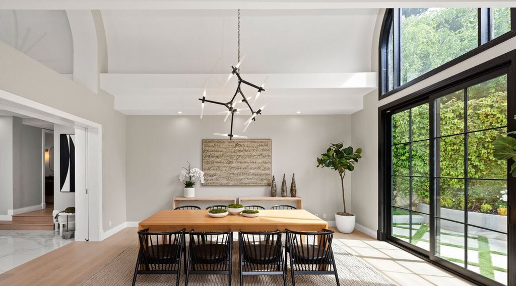Dining room beside a tall arched-head black aluminum-clad window wall overlooking the hedge garden, Beverly Hills remodel