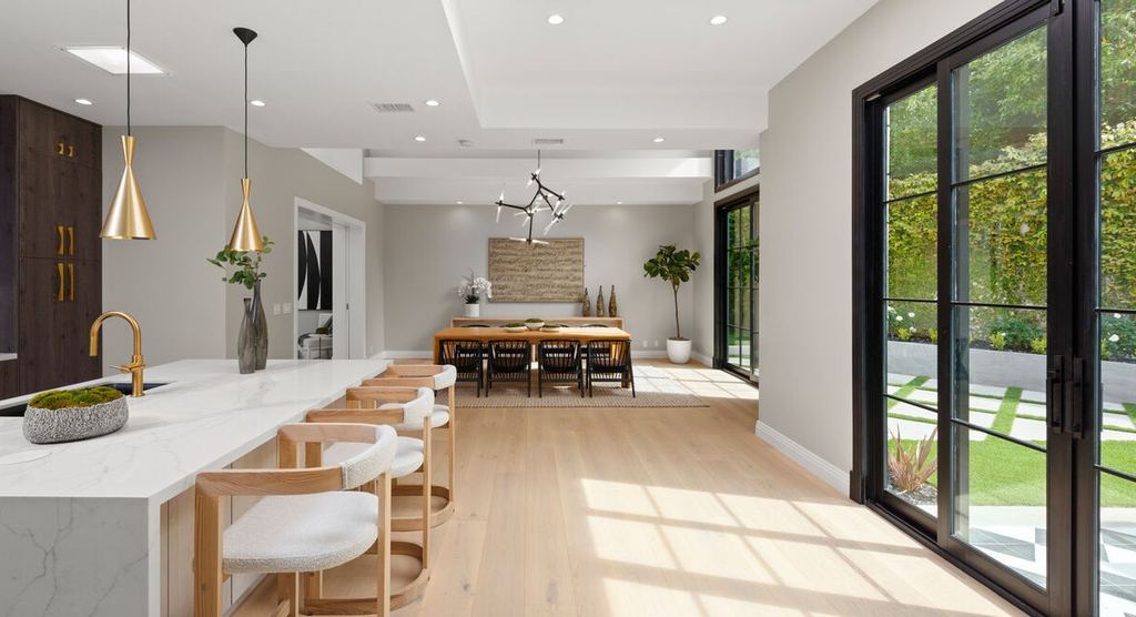 Kitchen and dining area with black aluminum-clad doors and windows framing the garden, Beverly Hills remodel