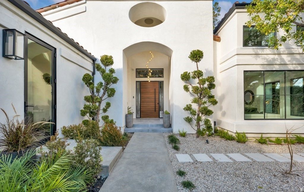White Spanish-style entry with arched doorway, wood pivot door, and steel-framed windows, Calabasas remodel