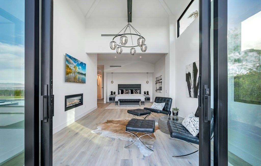 Primary bedroom viewed through black-framed glass doors with fireplace and valley view, Calabasas