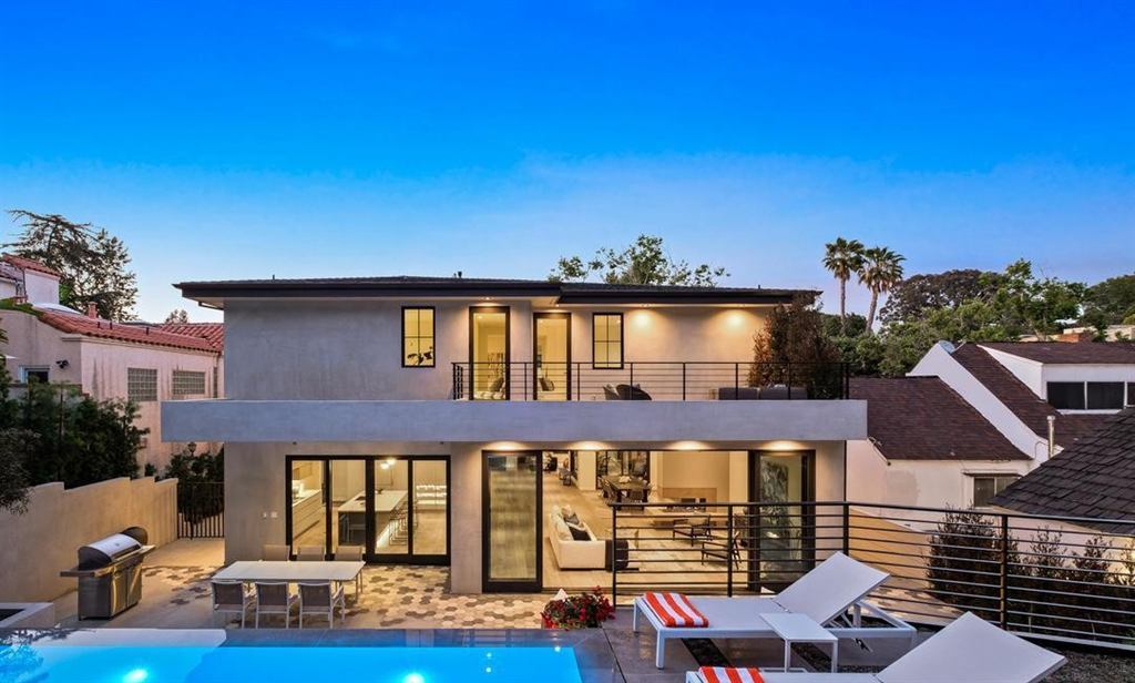 Rear exterior at dusk with dark aluminum multi-slide glass walls opening to the pool and patio, Cheviot Hills