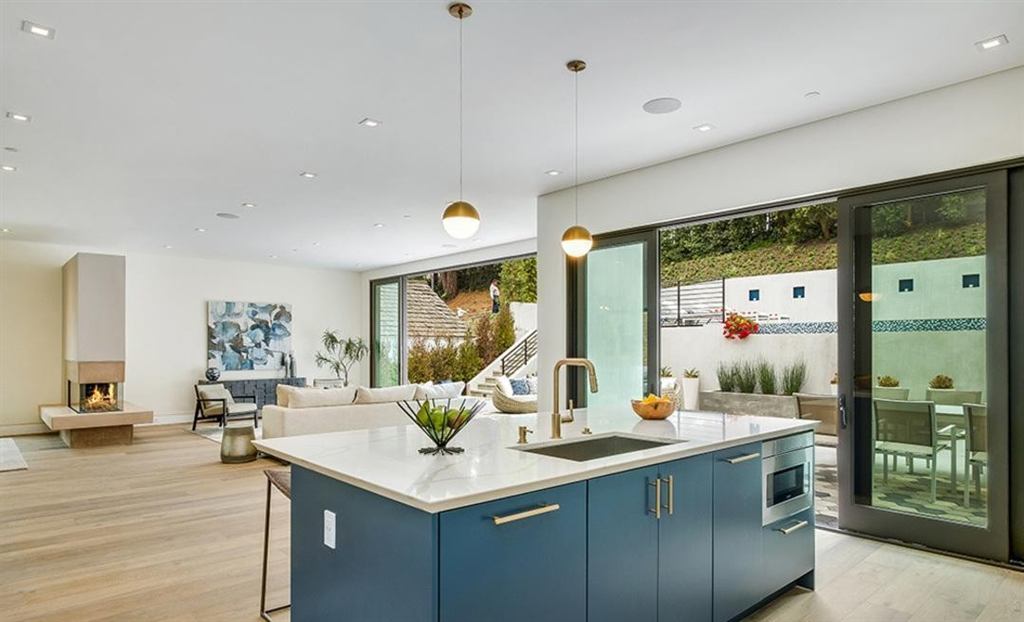 Kitchen with blue island opening through a dark aluminum multi-slide glass wall to the patio, Cheviot Hills