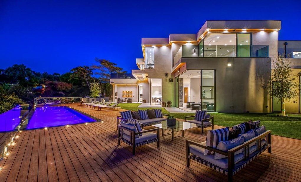 Blue-hour rear terrace of an Encino new-construction home with lounge seating, pool, and Arcadia aluminum glass walls along the elevation