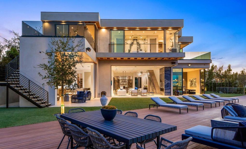 Dusk rear elevation in Encino showing a dining terrace beneath two storeys of Arcadia aluminum windows and sliding glass doors