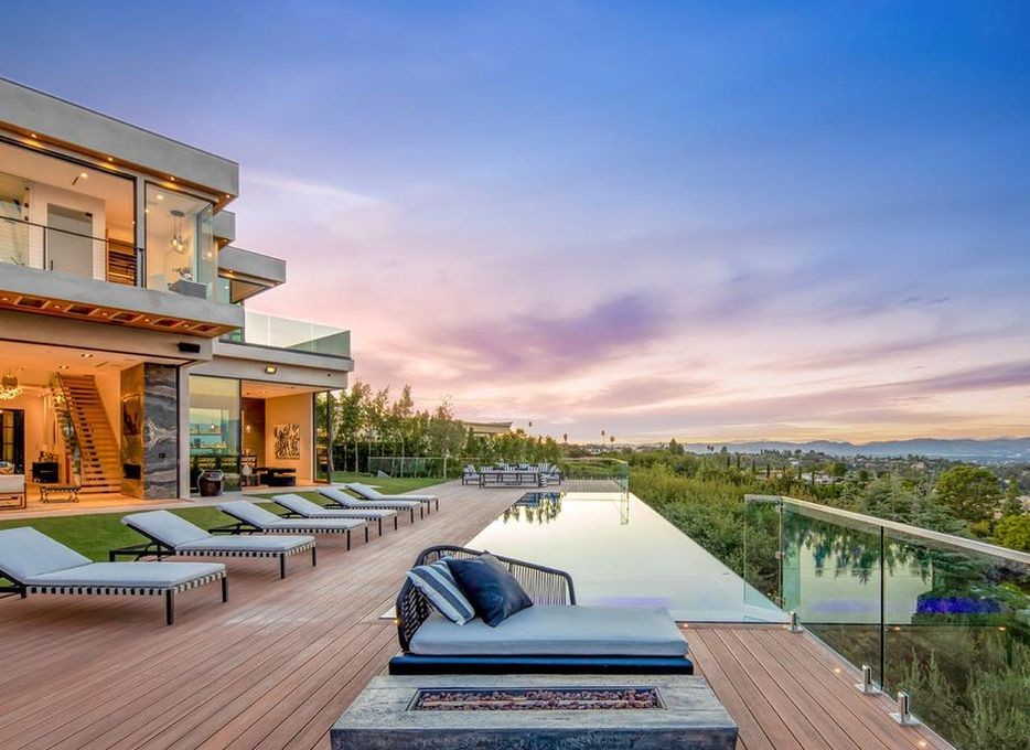 Sunset rear elevation of an Encino new-construction home, loungers beside the pool and Arcadia aluminum sliding doors opened across the ground floor