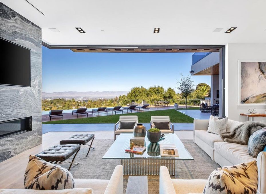 Living room with a stone fireplace wall and Arcadia aluminum sliding doors open to the pool, Encino new construction
