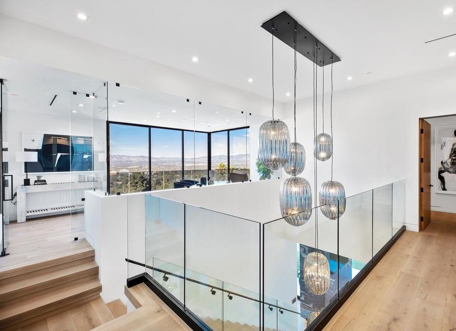 Upper landing and kitchen in Encino with a glass-railed stair and Arcadia aluminum glazing along the far wall