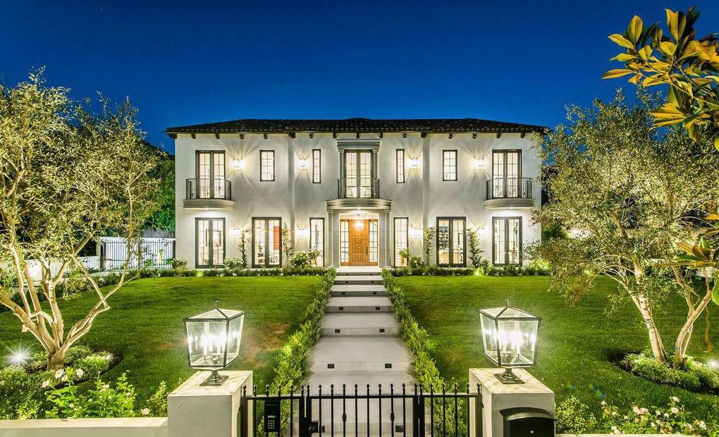 Front elevation at dusk of a white stucco Hancock Park home with Kolbe wood casement windows and Juliet balcony doors