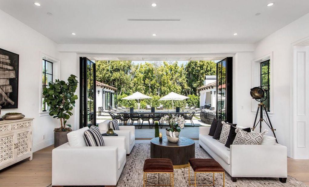 Living room with a wide folding wood door opened fully to the pool terrace and dining loggia, Hancock Park
