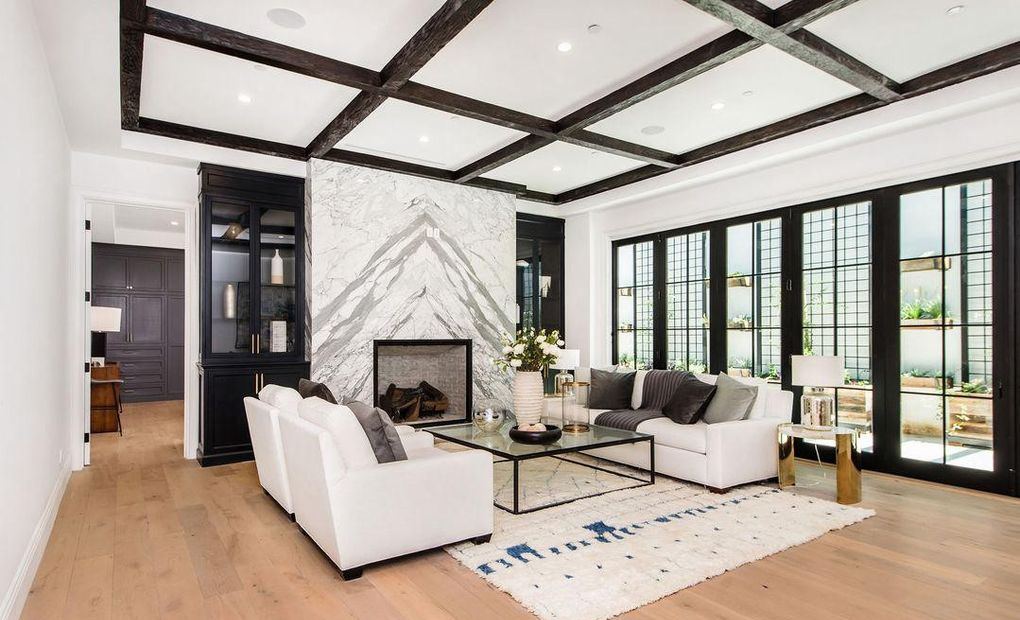 Living room with a run of divided-lite Kolbe wood doors and windows beside a marble fireplace, Hancock Park