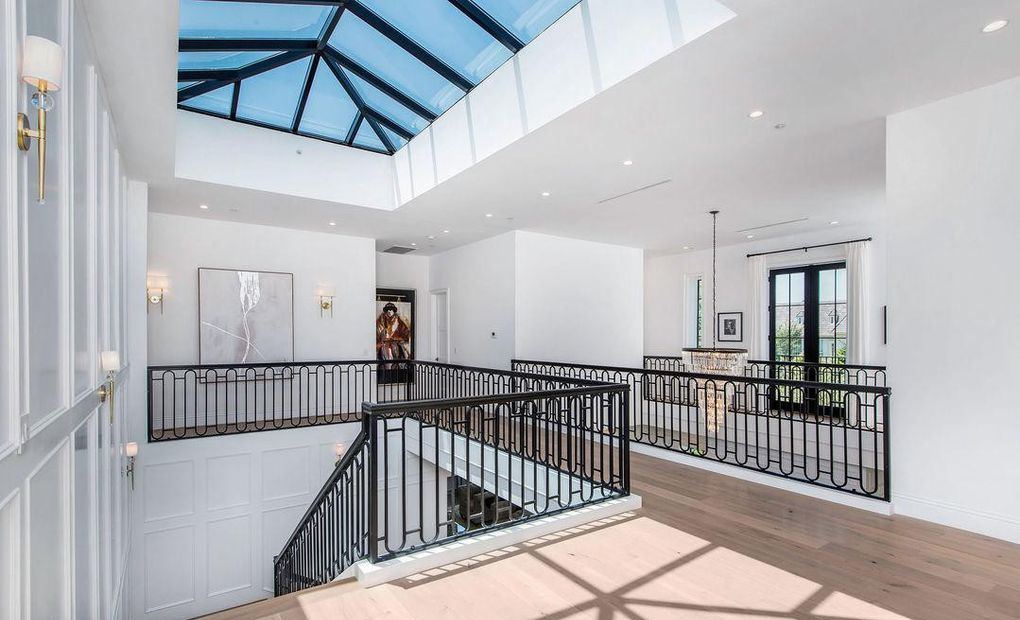 Upstairs landing beneath a gridded skylight with wrought-iron railings and wood windows beyond, Hancock Park