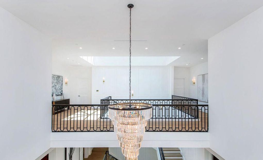 Second-floor landing with a tiered crystal chandelier over the stair void, Hancock Park new construction