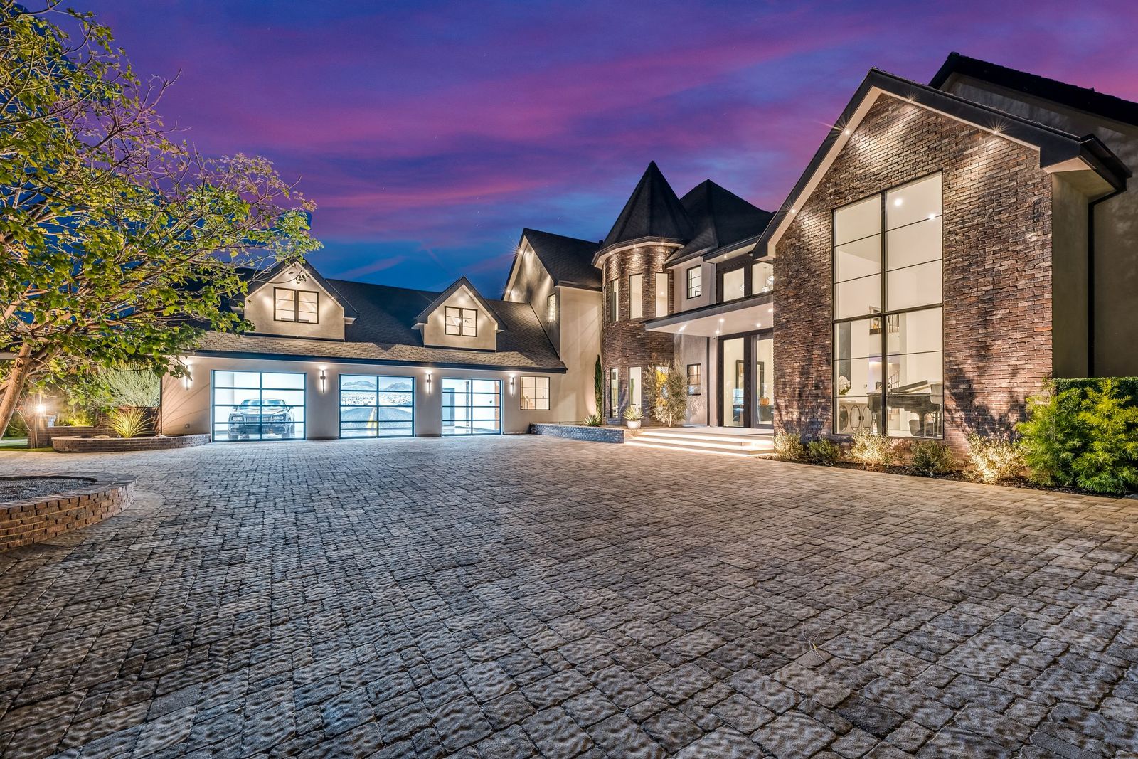 Woodland Hills remodel at dusk with a two-story aluminum window wall on the brick gable and glass garage doors