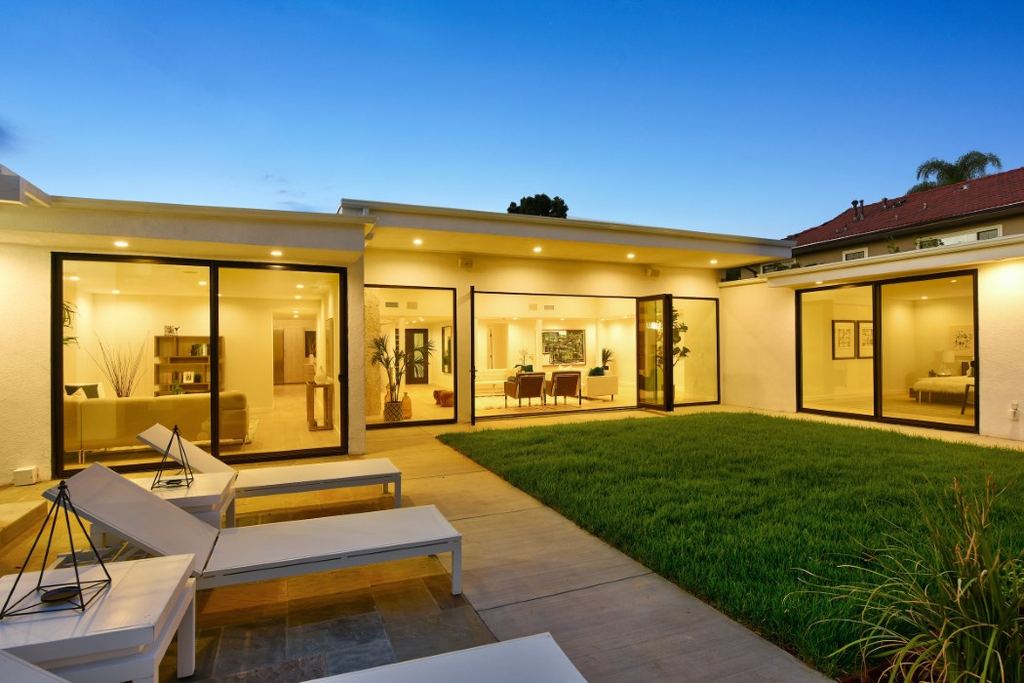 Los Feliz remodel backyard patio at dusk with black aluminum pocketing doors opening from the living room and primary suite