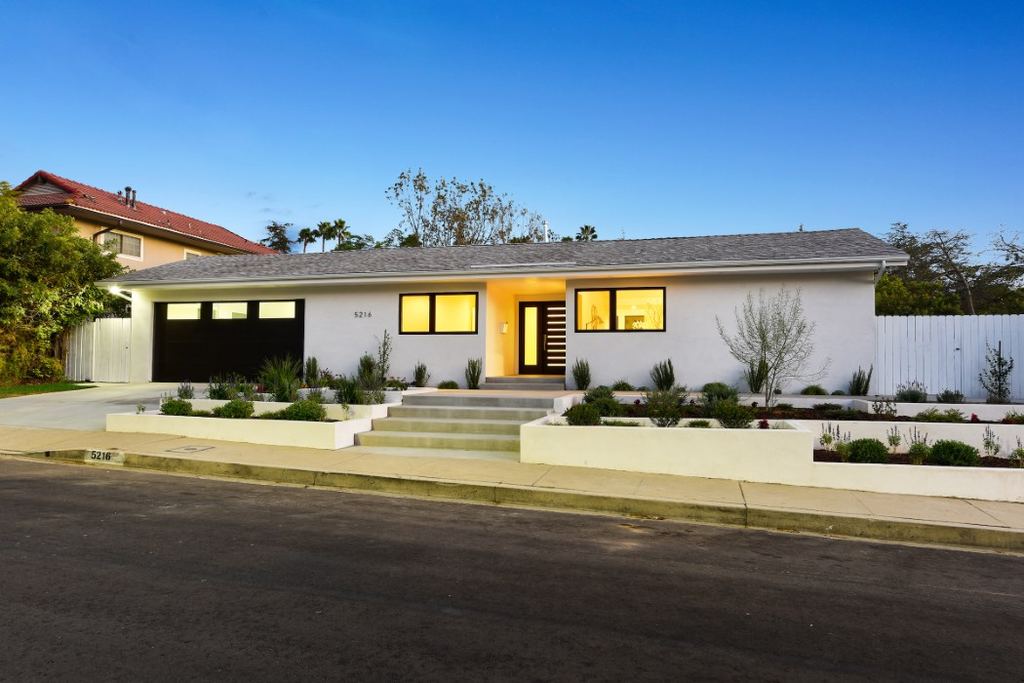 Los Feliz remodel front exterior at twilight with black-framed aluminum windows and a dark wood entry door