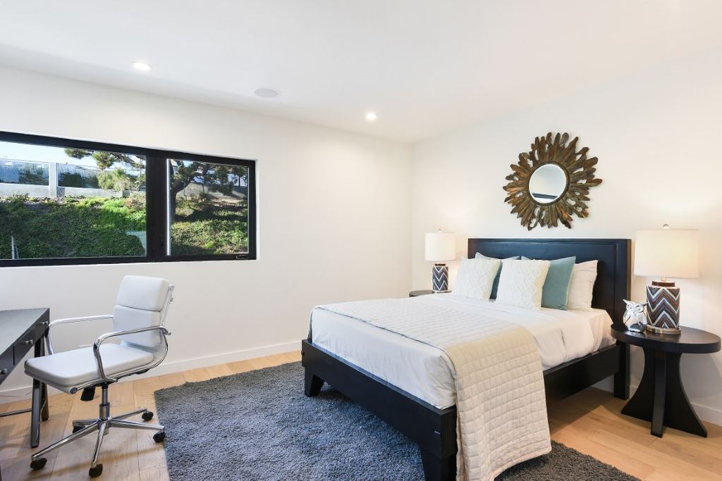 Bedroom with a black aluminum sliding window framing a hillside view, Los Feliz remodel