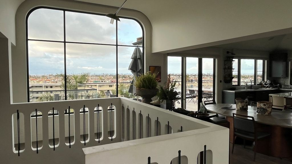 Second-story landing with an arched black steel picture window framing bay and harbor views, Newport Beach