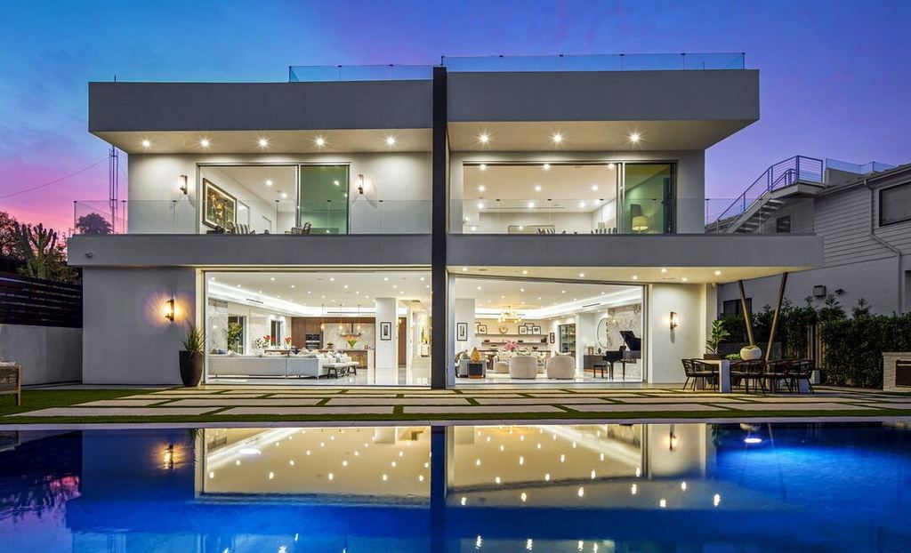 Blue-hour rear elevation in Pacific Palisades, the pool reflecting two storeys of Arcadia aluminum sliding doors and fixed glass