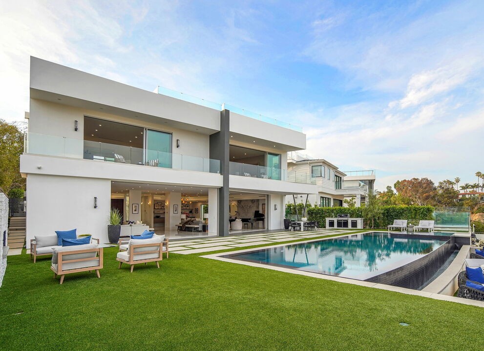 Daytime rear elevation of a Pacific Palisades new-construction home, lawn and pool below full-height Arcadia aluminum glazing