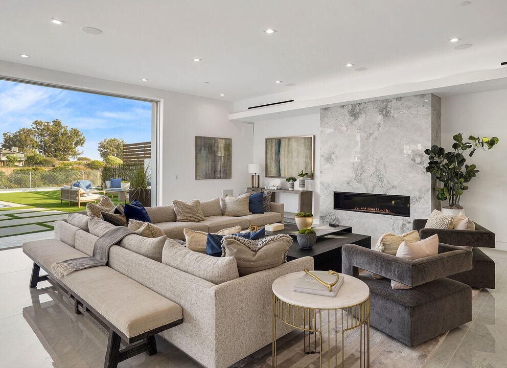 Open-plan living room in Pacific Palisades with a stone fireplace wall and Arcadia aluminum sliders onto the lawn