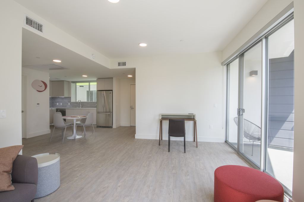 Open-plan living and dining area with an aluminum sliding door opening to a private patio, Studio City multifamily project