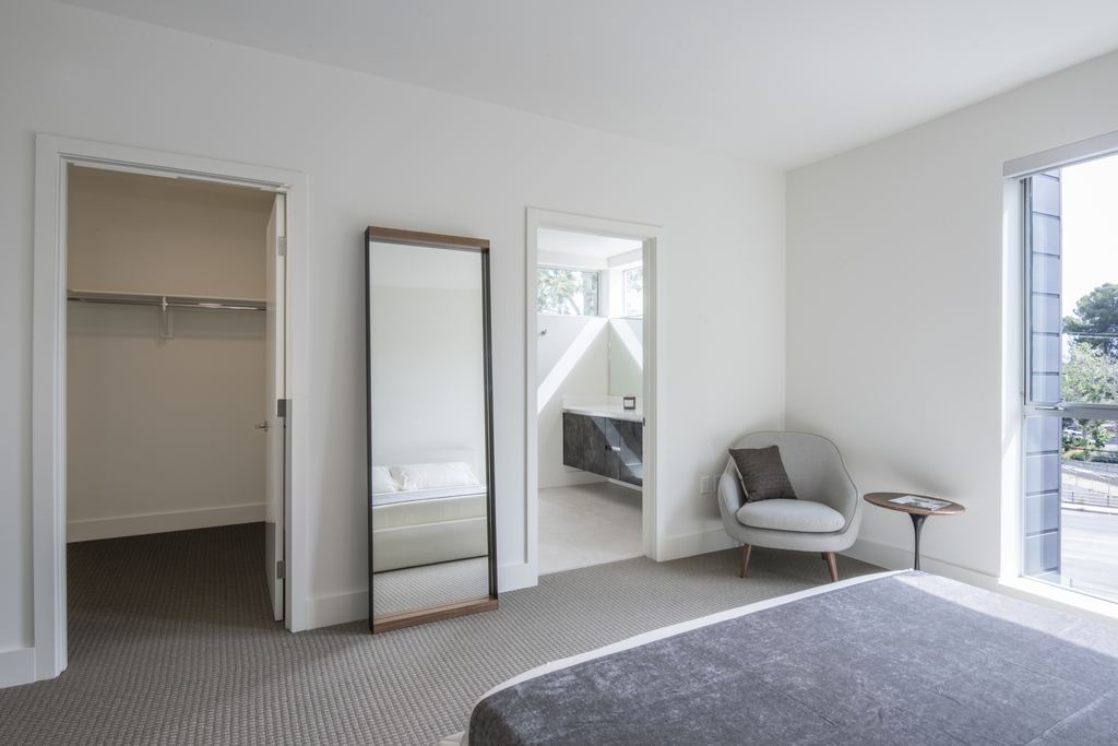 Bedroom with a full-height aluminum window to a balcony, walk-in closet and ensuite beyond, Studio City