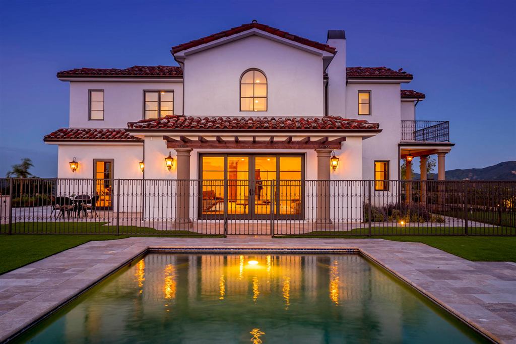 Spanish-style Topanga new construction rear exterior at dusk with a pool and arched window