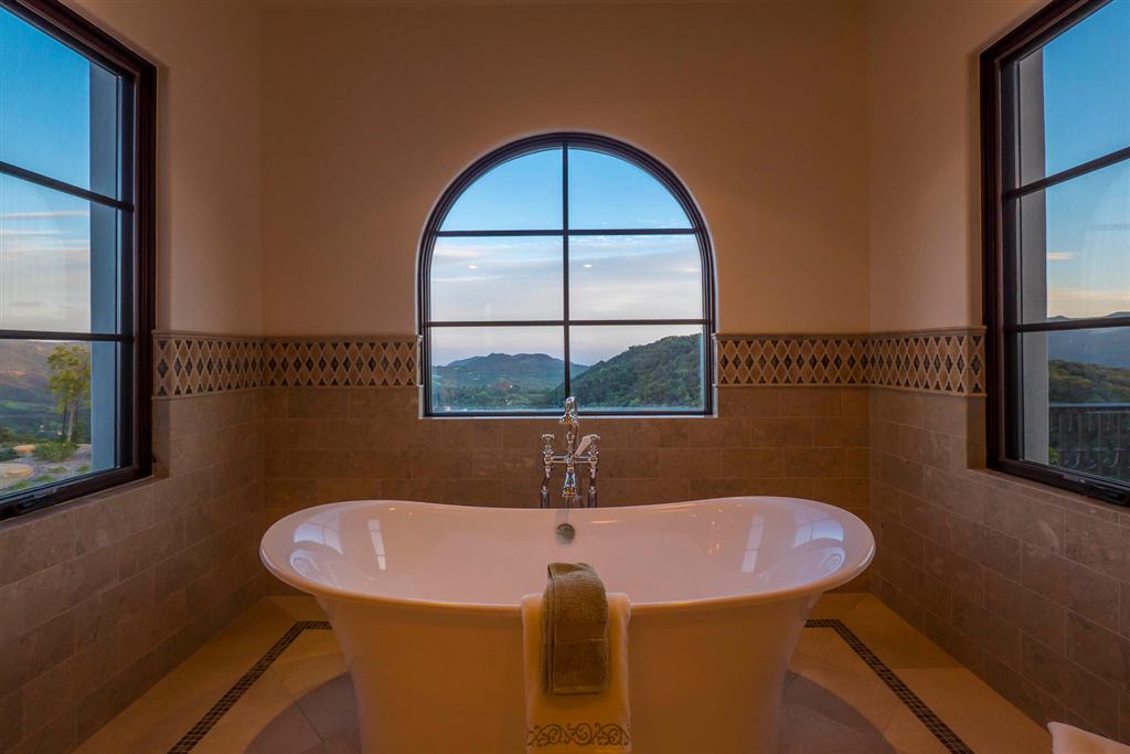 Primary bath with an arched aluminum window framing a valley view above the soaking tub, Topanga