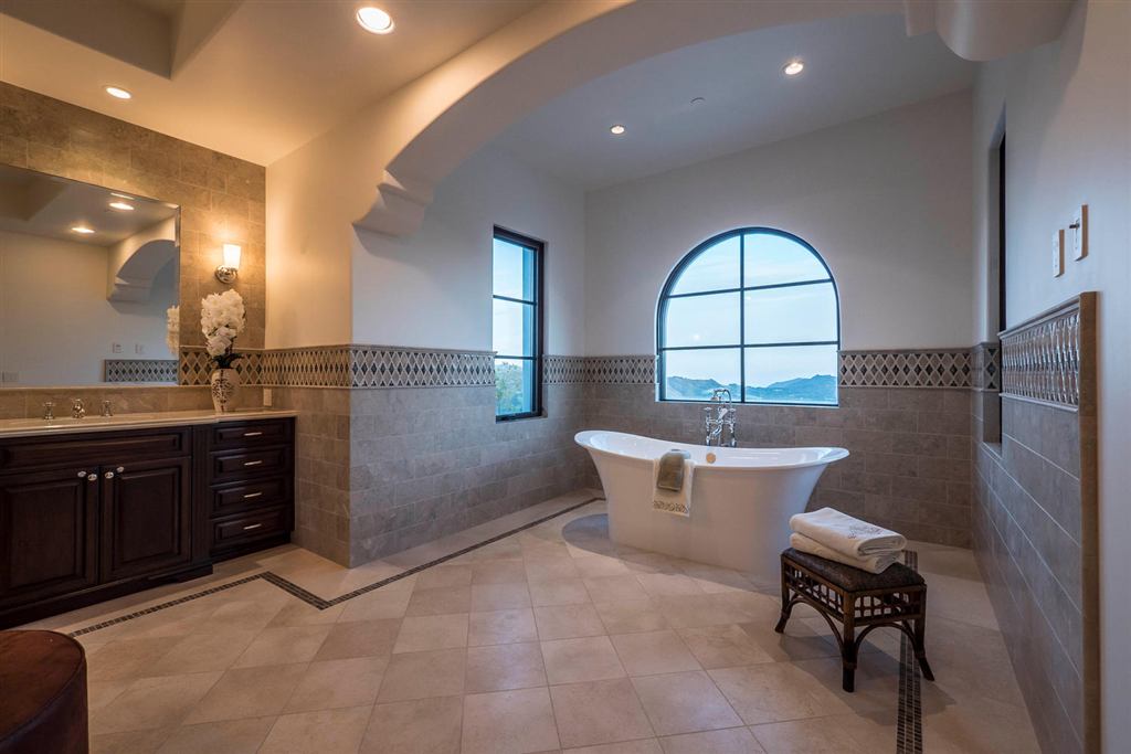 Bathroom with an arched window framing mountain views above a freestanding tub, Topanga new construction