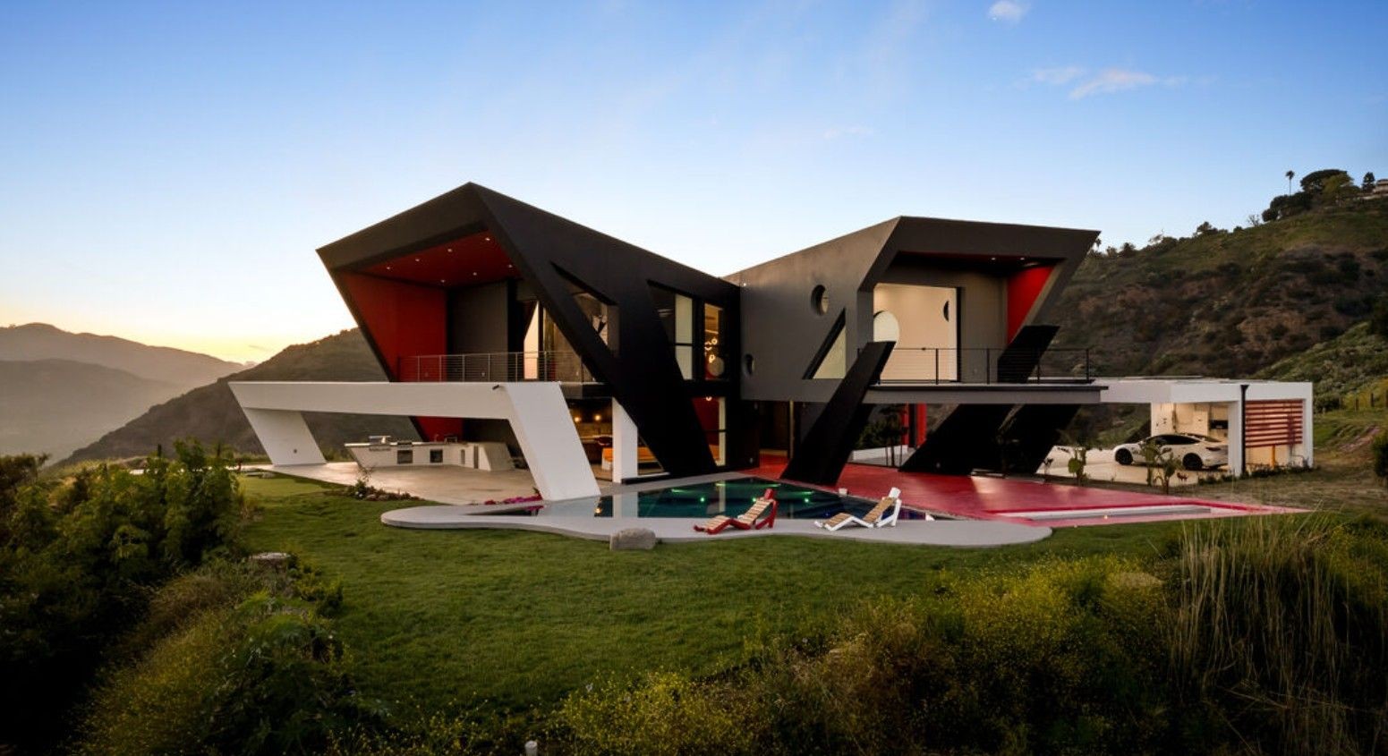 Modern hillside new construction in Topanga Canyon with floor-to-ceiling steel-framed glass overlooking the pool at dusk