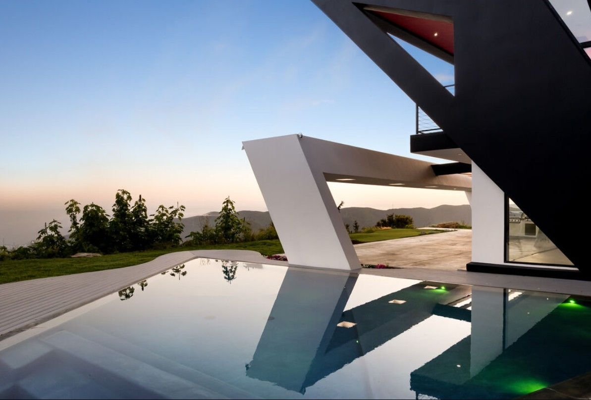 Infinity pool reflecting the cantilevered roofline and slim-sightline glazing of a Topanga Canyon modern home